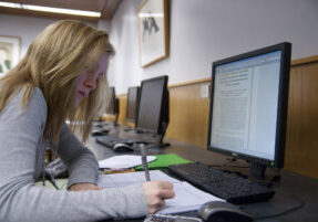 Person taking notes in front of a computer
